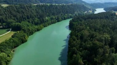 Gortina yakınlarındaki Drava nehrinin yaz drone görüntüleri, yeşil yamaçlar, durgun su, vadi kıvrımları, yumuşak akşam ışığı, barışçıl hava hareketi