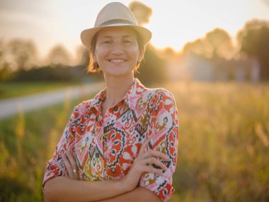 Yaz sonlarında Avrupa 'nın pitoresk alanlarında yürüyen genç bir kadın. Altın güneş ışığı, yemyeşil yemyeşil ve sakin kırsal atmosfer huzurlu bir kırsal alan yaratır..