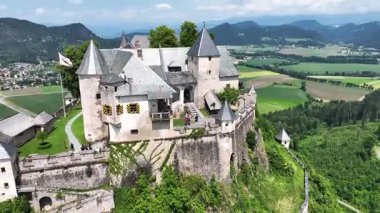 Tepedeki Hochosterwitz Kalesi 'ni, güçlendirilmiş duvarları, dramatik uçurumları, yaz renklerini, silip süpüren hava hareketlerini, tarihi dönüm noktalarını görüntüleyen sinematik dron görüntüleri.