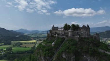 Tepedeki Hochosterwitz Kalesi 'ni, güçlendirilmiş duvarları, dramatik uçurumları, yaz renklerini, silip süpüren hava hareketlerini, tarihi dönüm noktalarını görüntüleyen sinematik dron görüntüleri.