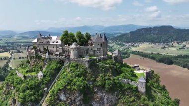Tepedeki Hochosterwitz Kalesi 'ni, güçlendirilmiş duvarları, dramatik uçurumları, yaz renklerini, silip süpüren hava hareketlerini, tarihi dönüm noktalarını görüntüleyen sinematik dron görüntüleri.