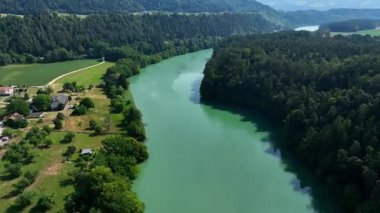 Gortina yakınlarındaki Drava nehrinin yaz drone görüntüleri, yeşil yamaçlar, durgun su, vadi kıvrımları, yumuşak akşam ışığı, barışçıl hava hareketi