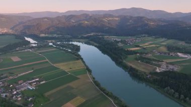 Drava Nehri 'nin mavi saat içindeki sinematik dron görüntüleri, derin renkler, durgun su, yumuşak eğimler, akşam durgunluğu, pürüzsüz hava hareketi, atmosferik yaz sahnesi