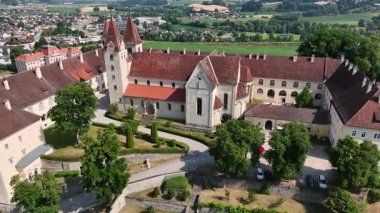 Sankt Paul im Lavanttal 'ın yaz havası manastır kompleksi, çatılar, vadi manzarası, yeşil tepeler, sakin sinema insansız hava aracı hareketi, sıcak atmosfer tonları.