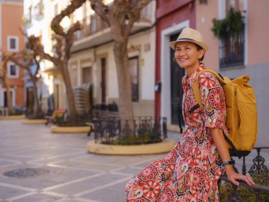 İspanyol kıyı kasabası La Vila Joiosa ya da Villajoyosa 'nın renkli caddelerinde gezen kadın. Güneşli kış atmosferi Akdeniz mimarisinin ve sakin deniz yaşamının cazibesini vurguluyor