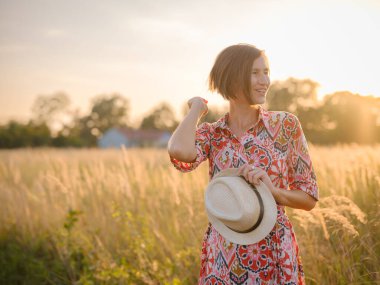 Yaz sonlarında Avrupa 'nın pitoresk alanlarında yürüyen genç bir kadın. Altın güneş ışığı, yemyeşil yemyeşil ve sakin kırsal atmosfer huzurlu bir kırsal alan yaratır..