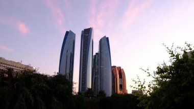 Abu Dabi Corniche Deniz Kenarı 'ndaki huzurlu park, bereketli palmiye ağaçları, gün batımı zamanı, dingin yollar. Sakin bir atmosfer yakalar, rahatlamak için ideal doğa yürüyüşleri ve şehrin doğal güzelliğinin tadını çıkarır..