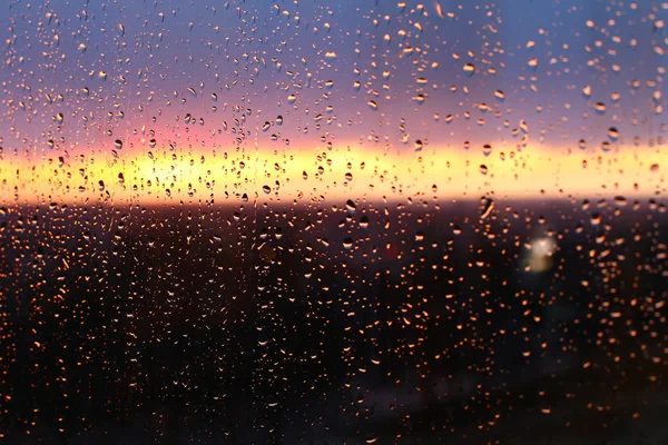 После дождя вода капает на оконное стекло. Небо с облаками и солнцем на фоне . — стоковое фото