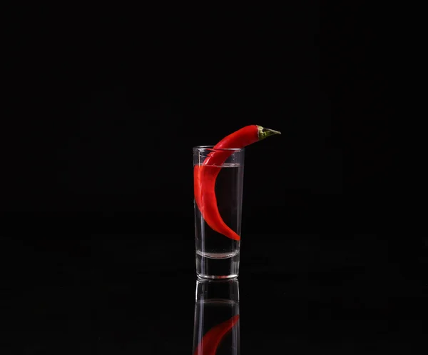Shot of vodka with chili peppers on a black background — Stock Photo, Image