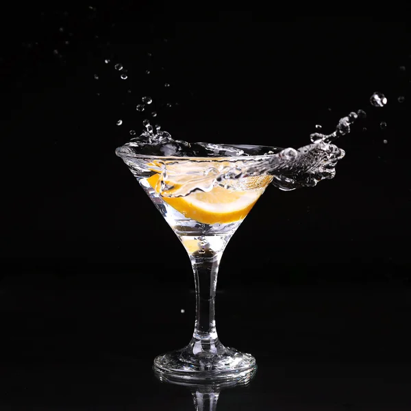 Cocktail martini espirrando em vidro no fundo preto — Fotografia de Stock