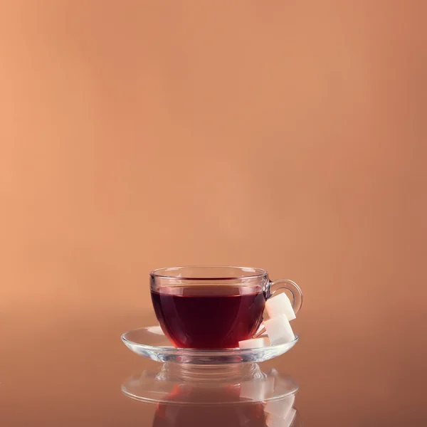 Taza de té sobre vidrio con fondo naranja — Foto de Stock