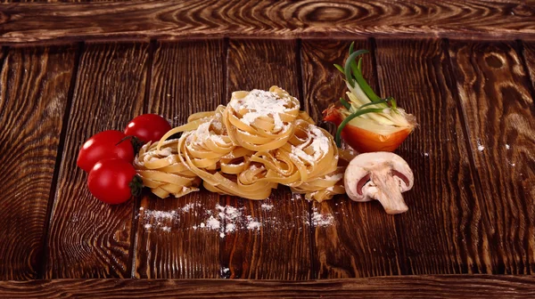 Vista superior en Pasta casera cruda con tomates, y harina sobre ol — Foto de Stock