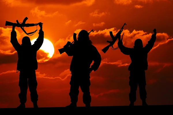Silhueta de soldado militar ou oficial com armas ao pôr do sol. tiro, segurando arma, céu colorido, montanha, fundo — Fotografia de Stock