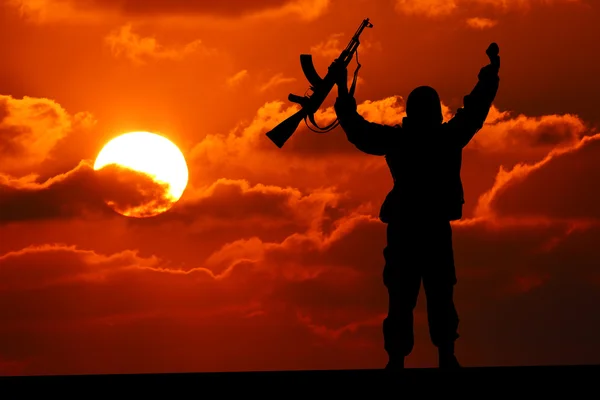 Silhouet van militaire soldaat of officier met wapens bij zonsondergang. schot, houden pistool, kleurrijke hemel, berg, achtergrond — Stockfoto