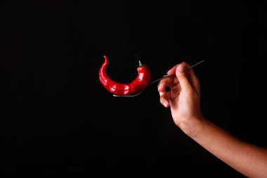 Çatal kazığa oturtmak için siyah arka plan üzerinde kırmızı sıcak biber.