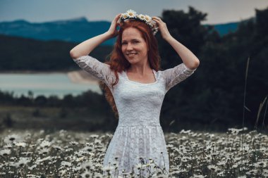 Papatya alanındaki kıvırcık kırmızı saçlı güzel genç kız