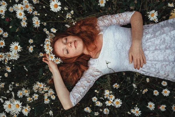 Hermosa joven con el pelo rojo rizado en el campo de manzanilla — Foto de Stock