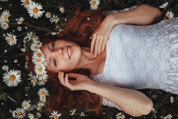 Belle jeune fille aux cheveux roux bouclés dans un champ de camomille — Photo