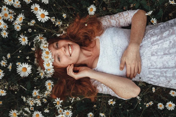 Belle jeune fille aux cheveux roux bouclés dans un champ de camomille — Photo