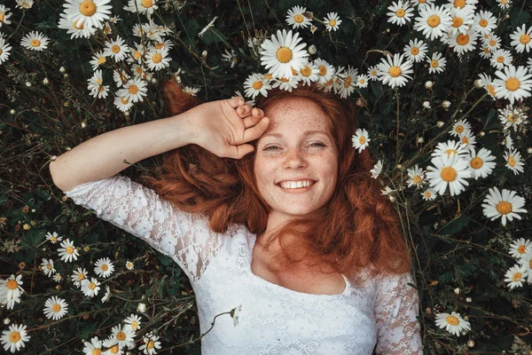 Menina bonita com cabelo encaracolado vermelho no campo de camomila — Fotografia de Stock