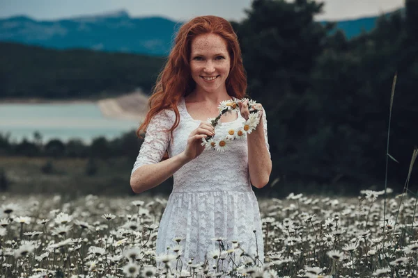 Όμορφη νεαρή κοπέλα με σγουρά μαλλιά κόκκινο στο πεδίο χαμομήλι — Φωτογραφία Αρχείου
