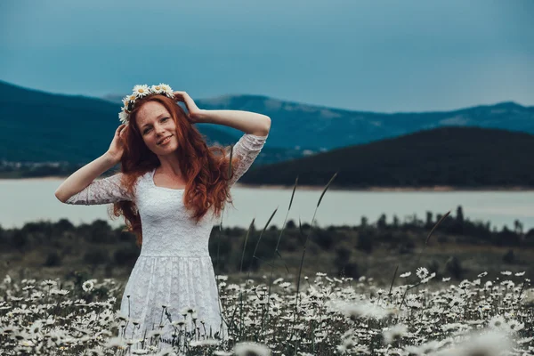 Krásná mladá dívka s kudrnatými vlasy červená heřmánku poli — Stock fotografie