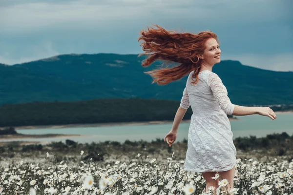 Красива молода дівчина з кучерявим рудим волоссям в ромашковому полі — стокове фото