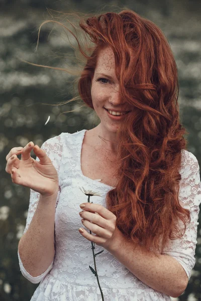 Menina bonita com cabelo encaracolado vermelho no campo de camomila — Fotografia de Stock