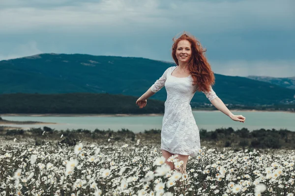 Krásná mladá dívka s kudrnatými vlasy červená heřmánku poli — Stock fotografie