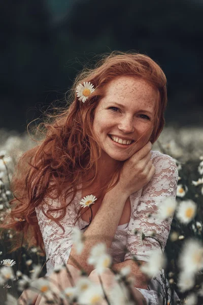 Menina bonita com cabelo encaracolado vermelho no campo de camomila — Fotografia de Stock