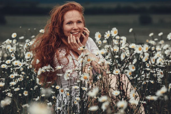 Menina bonita com cabelo encaracolado vermelho no campo de camomila — Fotografia de Stock