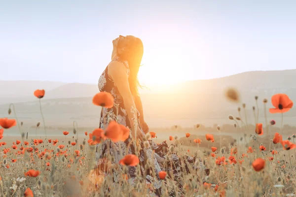 Menina bonita em um campo de papoula ao pôr do sol. conceito de liberdade — Fotografia de Stock