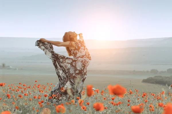 Bella ragazza in un campo di papaveri al tramonto. concetto di libertà — Foto Stock