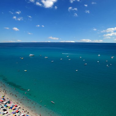 Turkuvaz suyu ve kumu olan deniz plajı insanların dinlendiği, yüzdüğü ve şemsiyelerle güneşlendiği yer.