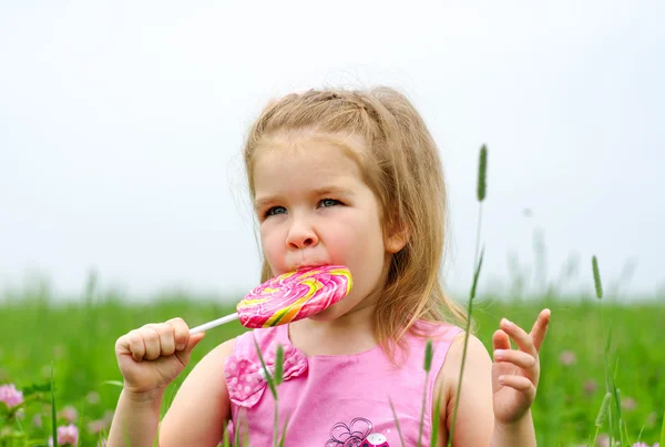 A kislány nyalókát eszik. — Stock Fotó