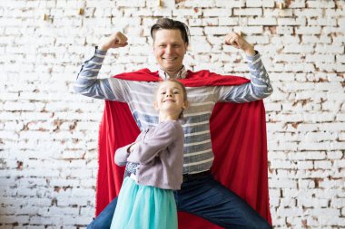 Süper kahraman kostümlü mutlu bir baba ve kızı.