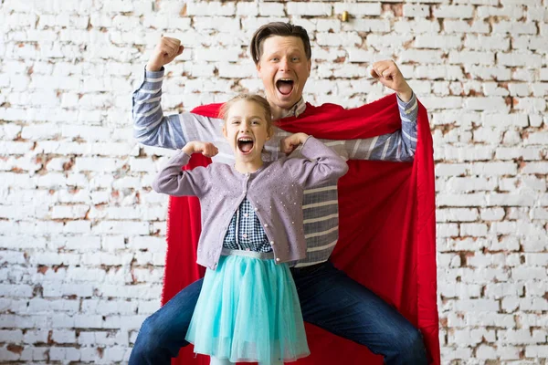 Lycklig far i superhjältedräkt och hans dotter — Stockfoto