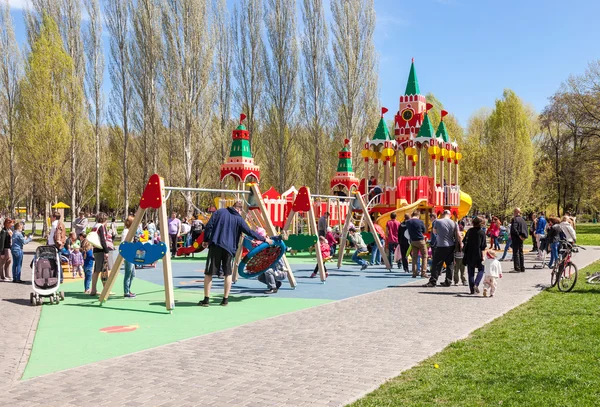 I bambini giocano nel parco giochi del parco primaverile nella giornata di sole — Foto Stock