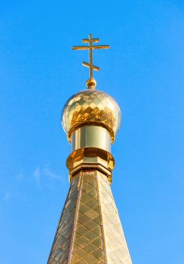 Mavi gökyüzüne karşı haçı olan Rus Ortodoks Kilisesi 'nin altın kubbesi
