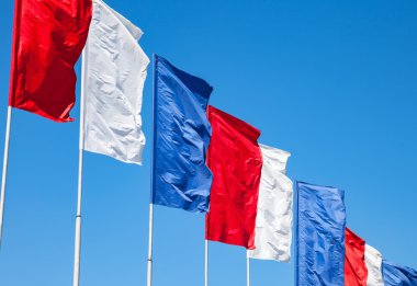 Beyaz, kırmızı ve mavi bayraklar sallayarak üzerinde mavi gökyüzü arka plan