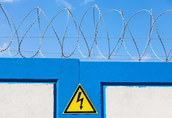 Barbed wire on the fence against a blue sky background — Stock Photo, Image