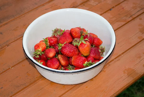 Enamelled bowl with fresh strawberries standing on the rustic wo — Stock Photo, Image