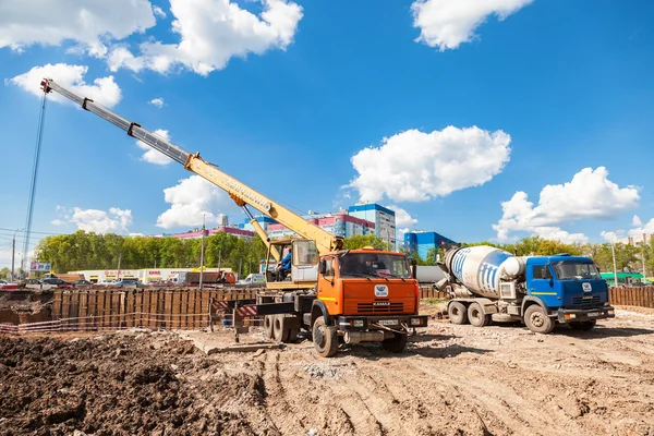 Teherautó daru KAMAZ és betonkeverő teherautó dolgozik a építés — Stock Fotó