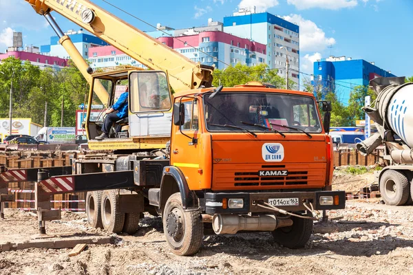 Guindaste de caminhão KAMAZ trabalhando no canteiro de obras sob constr — Fotografia de Stock