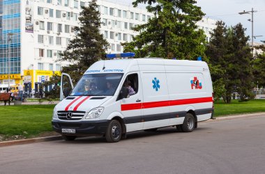 Ambulans araba sokakta park edilmiş. Metin Rusça: 