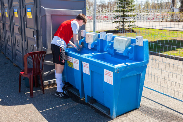 Unidentified athlete washes his hands in the mobile sink near th