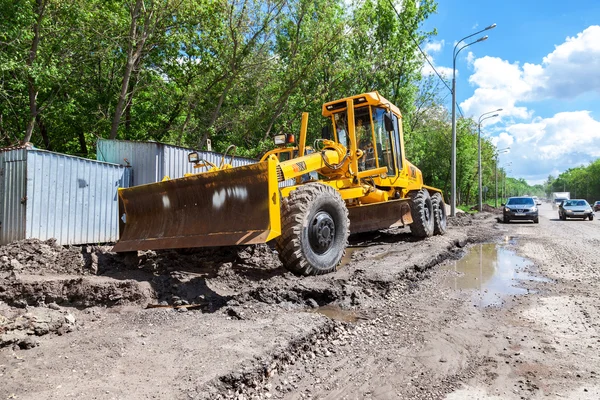 Grader estrada pesada estacionada perto da estrada em construção — Fotografia de Stock