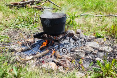 Bir kamp ateşi, açık havada yaz güneşli bir günde pişirme