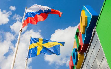 Rusya ve İsveç bayraklarını sallayarak mavi gökyüzü karşı sh