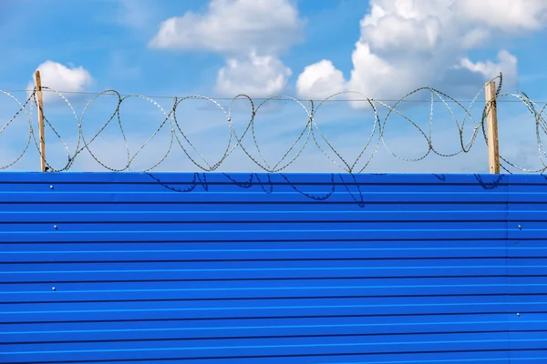 Alambre de púas en la valla contra un fondo azul del cielo. Restringir — Foto de Stock